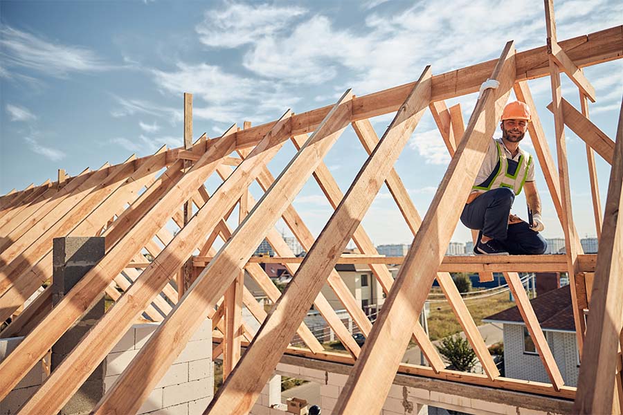 Specialized Business Insurance - Portrait of a Smiling Contractor Working on Building the Frame of a Roof for a New Home